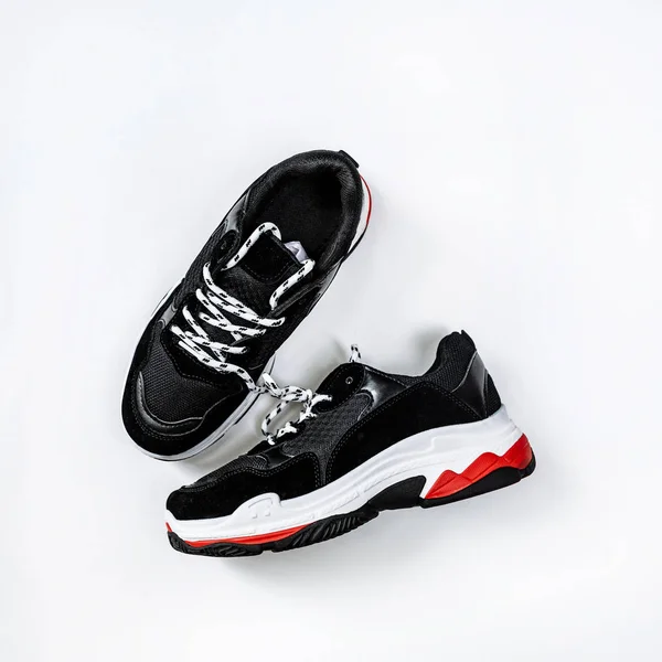 Black sneakers on thick white with red accents soles on a white background — Stock Photo, Image