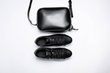 beyaz arka plan üzerinde beyaz taban ve siyah deri çanta ile siyah deri spor ayakkabı