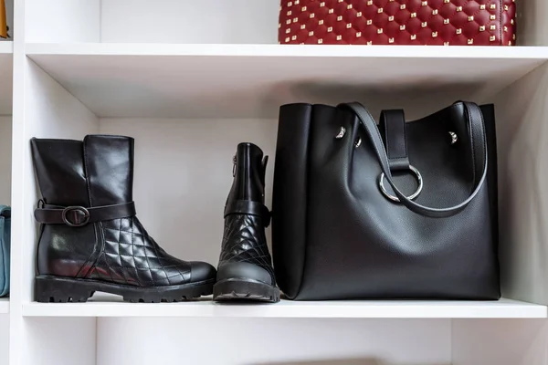 Paio di scarpe in pelle nera con tacco basso e una borsa nera su uno scaffale bianco nel negozio — Foto Stock