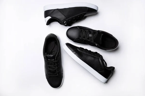 四个黑色皮革运动鞋与白色鞋底白色背景 — 图库照片