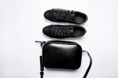 beyaz arka plan üzerinde beyaz taban ve siyah deri çanta ile siyah deri spor ayakkabı