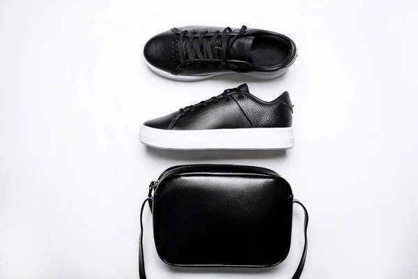 Black leather sneakers with white sole and black leather bag on a white background — Stock Photo, Image