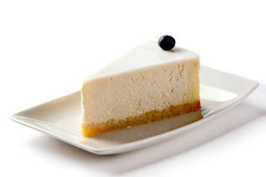 izole beyaz bir arka plan üzerinde beyaz bir tabakta yaban mersini ile süslenmiş cheesecake parçası