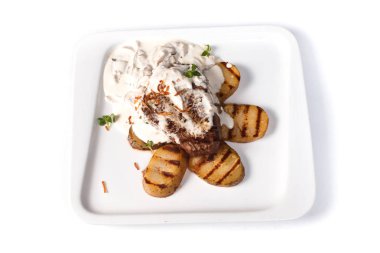 izole beyaz bir arka plan üzerinde bir kare tabak üzerinde beyaz bir tencerede patates ile kızarmış biftek