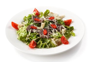 izole beyaz bir arka plan üzerinde bir tabakta peynir, otlar ve domates ile et salatası