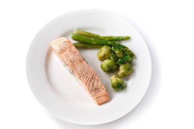 izole beyaz bir arka plan üzerinde bir tabak brüksel lahanası ve kuşkonmaz ile ızgara kırmızı balık biftek