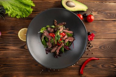Ahşap arka plan üzerinde siyah tabak tay sığır salatası