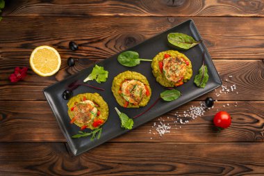 siyah bir tabakta yeşil bezelye püresi ile deniz pirzola