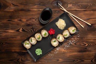 dikdörtgen siyah bir tabak üzerinde peynir ve otlar ile rulo bir dizi