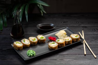 dikdörtgen siyah bir tabak üzerinde peynir ve otlar ile rulo bir dizi