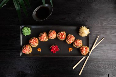 siyah ahşap arka plan üzerinde siyah dikdörtgen plaka üzerinde suşi rulo seti