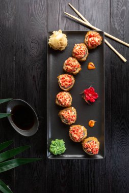 siyah ahşap arka plan üzerinde siyah dikdörtgen plaka üzerinde suşi rulo seti