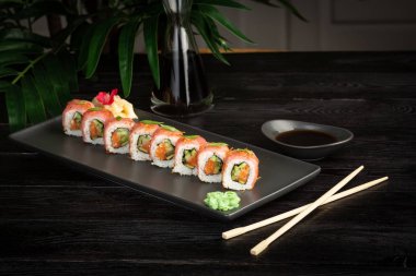 siyah ahşap arka plan üzerinde siyah dikdörtgen plaka üzerinde suşi rulo seti