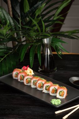 siyah ahşap arka plan üzerinde siyah dikdörtgen plaka üzerinde suşi rulo seti