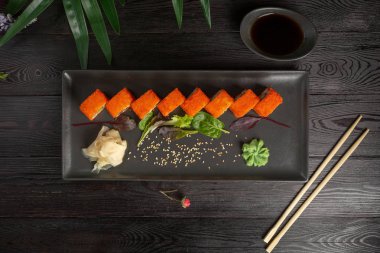 siyah ahşap arka plan üzerinde siyah dikdörtgen plaka üzerinde suşi rulo seti