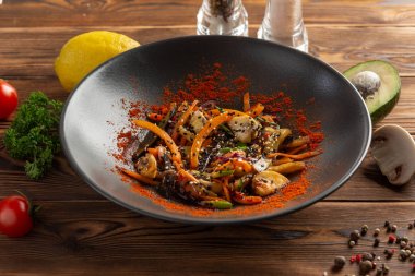 Siyah tabakta baharatlı tavuklu sebzeler.