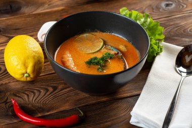 siyah bir tabakta çorba tom yam 