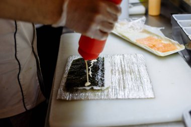 restoranın mutfağında masada bir tahta üzerinde rulo hazırlanması