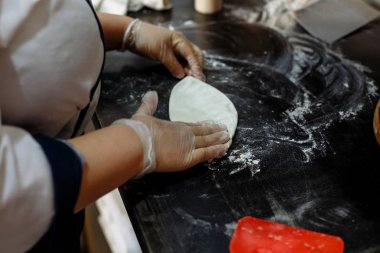 bir restoran mutfakta siyah bir tahta üzerinde hamur yoğurunur eldiven pişirmek