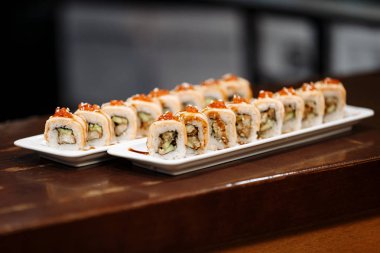 Ahşap bir masa üzerinde dikdörtgen plakalar üzerinde suşi setleri