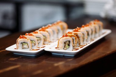 Ahşap bir masa üzerinde dikdörtgen plakalar üzerinde suşi setleri