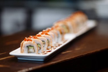 Suşi ahşap bir masa üzerinde dikdörtgen bir plaka üzerinde ayarlayın