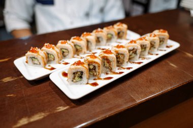 Ahşap bir masa üzerinde dikdörtgen plakalar üzerinde suşi setleri