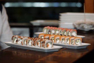 Ahşap bir masa üzerinde dikdörtgen plakalar üzerinde suşi setleri