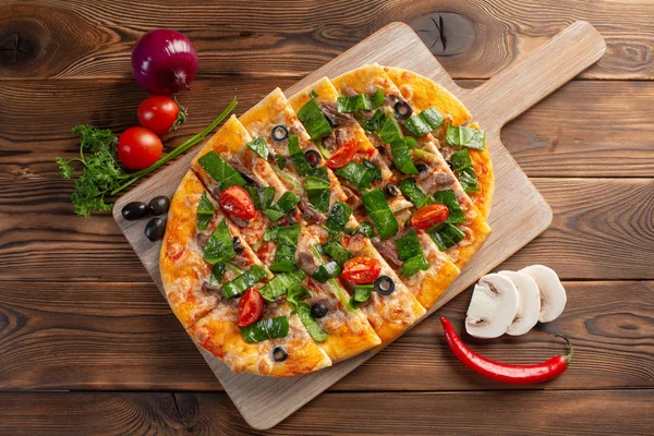 ahşap bir arka plan üzerinde dana eti ve kurutulmuş domates ile pizza