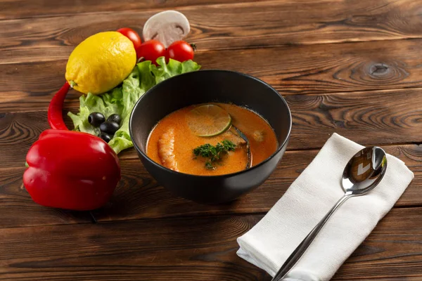 siyah bir tabakta çorba tom yam 