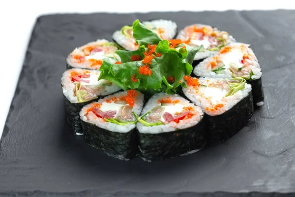 Rollos de sushi sobre pizarra negra sobre fondo blanco aislado —  Fotos de Stock