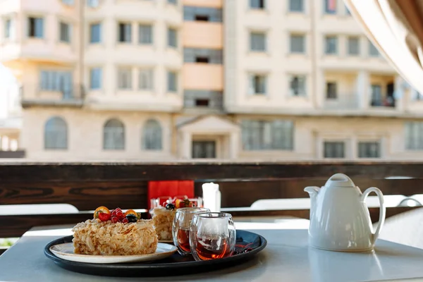 Bricka med Tekanna, muggar och kakor på ett bord i ett kafé mot fönstret — Stockfoto