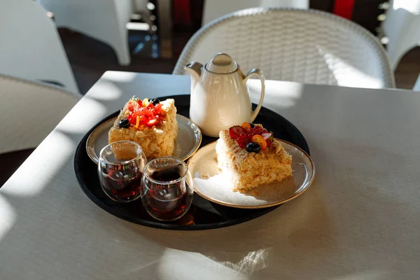 Bandeja con una tetera, tazas y pasteles en una mesa en un café — Foto de Stock