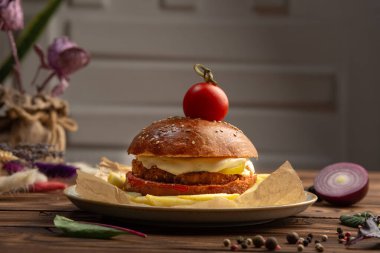 Çeri domatesli çizburger ahşap bir masada.