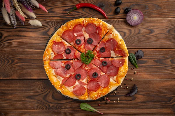 Sosisli dilimlenmiş pizza ve ahşap arka planda siyah zeytin.