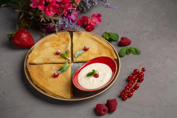 Tortitas con crema agria, dobladas por un triángulo en un plato — Foto de Stock