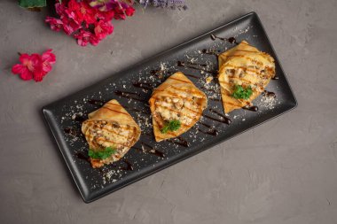 Julienne ile doldurulmuş gözlemeler ve yeşilliklerle süslenmiş.