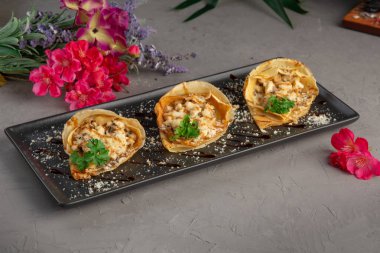 Julienne ile doldurulmuş gözlemeler ve yeşilliklerle süslenmiş.