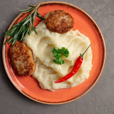 Turuncu tabakta patates püresi ve et pirzolası.