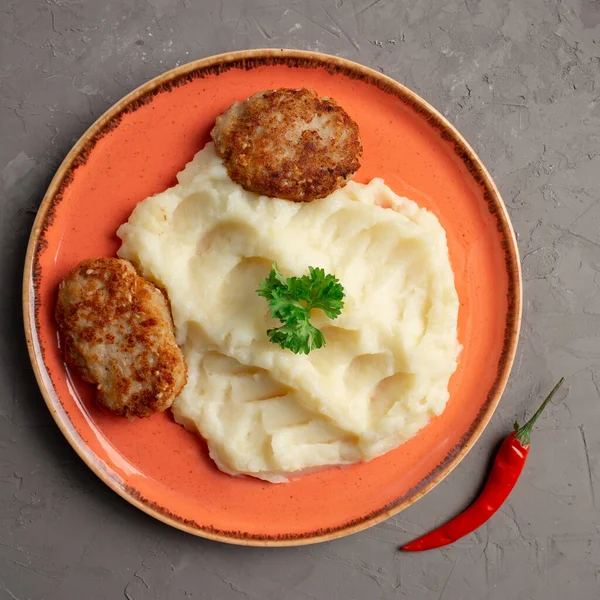 Turuncu tabakta patates püresi ve et pirzolası.