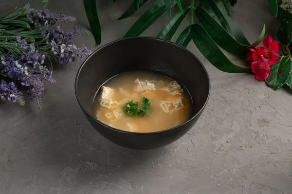 Суп з курячої локшини у формі серця в чорній тарілці — стокове фото