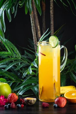 Koyu bir arka planda meyve dolu bir sürahide ananas kokteyli.