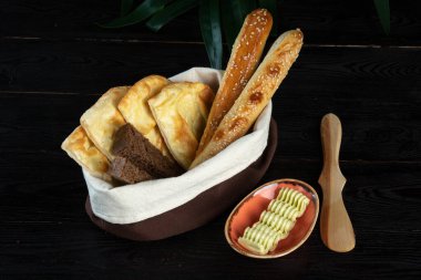 Sepette çeşitli ekmek ve koyu bir arka planda bir fincanda sos.