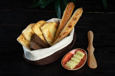 Sepette çeşitli ekmek ve koyu bir arka planda bir fincanda sos.