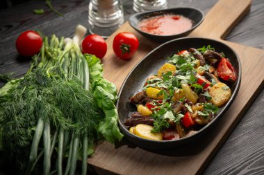 Siyah oval bir tabakta biftek. Koyu bir arka planda tahta bir tahta üzerinde.