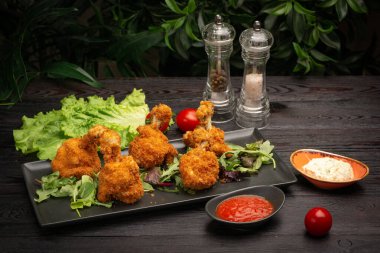 Baharatlı soslu tavuk kanadı ve siyah tahtada otlar.