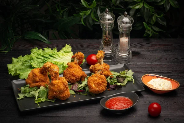 Baharatlı soslu tavuk kanadı ve siyah tahtada otlar.