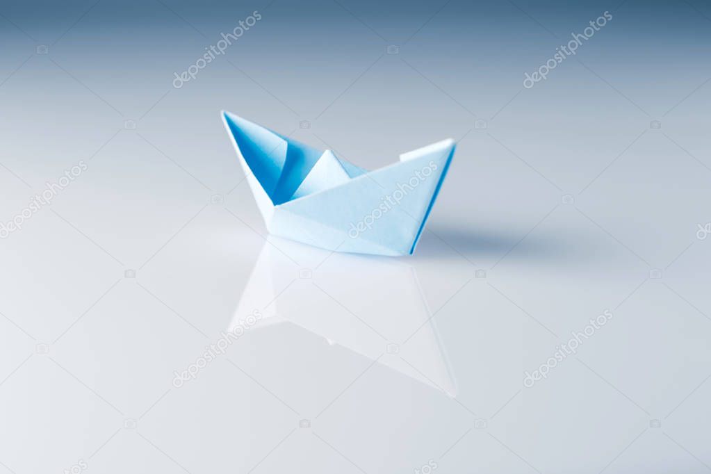 paper boat with reflection on shiny surface