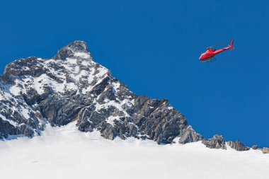 Alpler üzerinde uçan kırmızı helikopter
