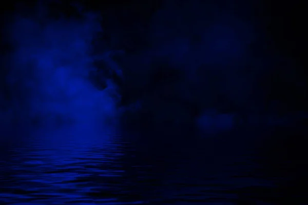 Синие катящиеся волны дымового тумана облака из льда по дну света с отражением в воде . — стоковое фото